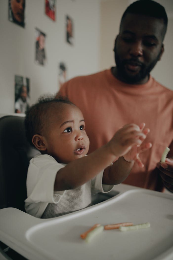 A father lovingly interacts with his baby during a meal at home.